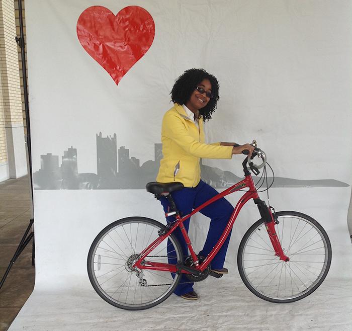 person standing with a bike, with drawing of Pittsburgh city skyline in the background